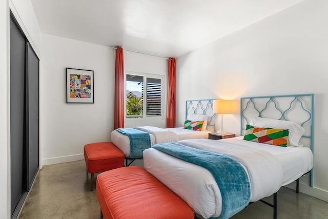 bedroom with concrete flooring and a closet