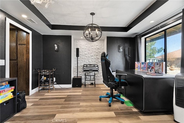 office area with an inviting chandelier, hardwood / wood-style floors, and a tray ceiling