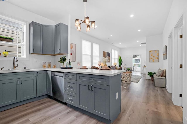 kitchen featuring kitchen peninsula, stainless steel dishwasher, light hardwood / wood-style floors, sink, and gray cabinets