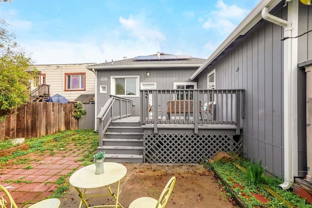 rear view of house with a wooden deck and solar panels