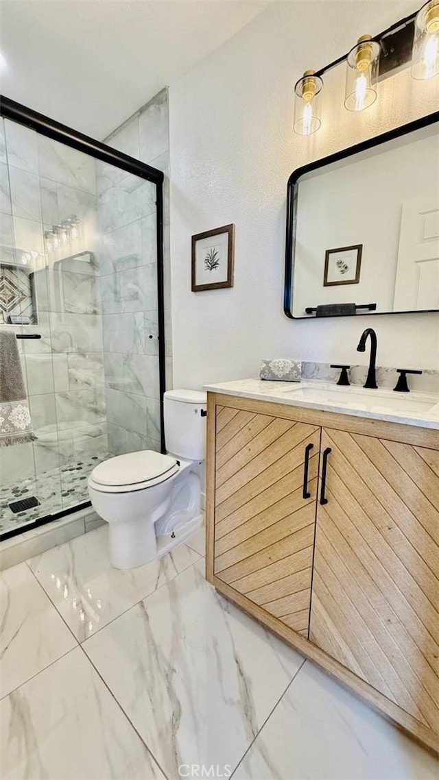 bathroom with a shower with shower door, vanity, and toilet