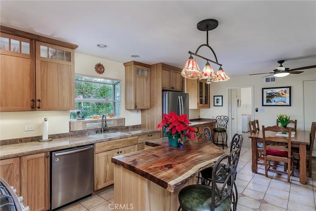 kitchen featuring ceiling fan, stainless steel appliances, decorative light fixtures, a kitchen island, and sink