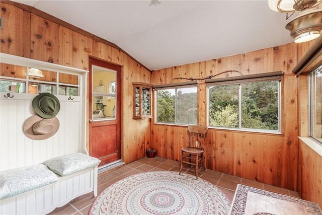 interior space featuring tile patterned flooring, wood walls, and vaulted ceiling