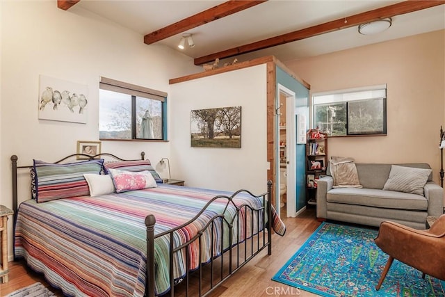 bedroom featuring beamed ceiling and light hardwood / wood-style flooring