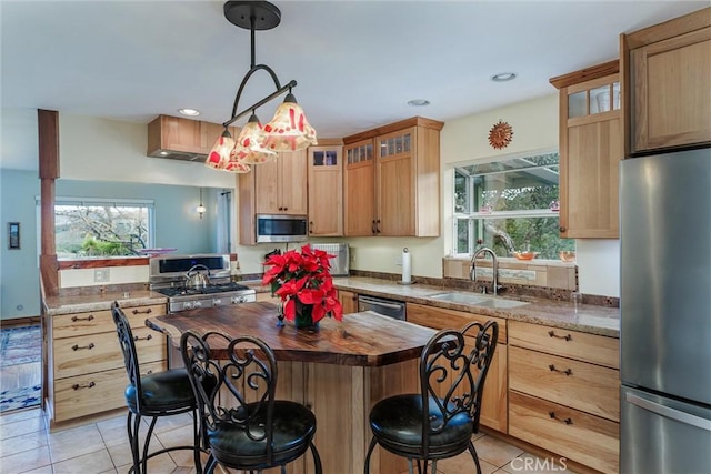 kitchen with light tile patterned floors, stainless steel appliances, pendant lighting, light stone counters, and sink