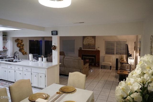 dining space featuring light tile patterned floors, a fireplace, and sink