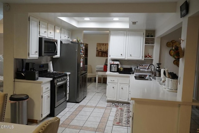 kitchen with white cabinets, sink, gas range, light tile patterned floors, and a tray ceiling