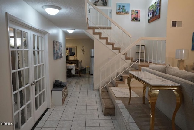 stairway with a textured ceiling, french doors, and tile patterned flooring