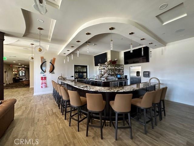 bar featuring stone counters and hardwood / wood-style flooring