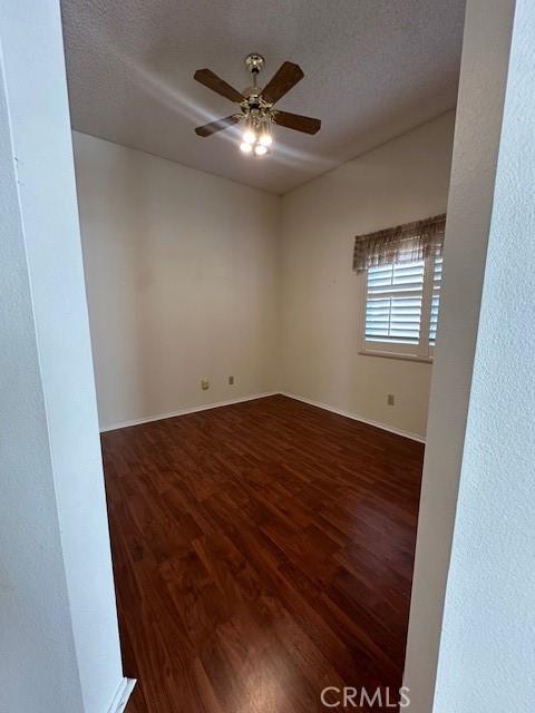 empty room with dark hardwood / wood-style floors, a textured ceiling, and ceiling fan