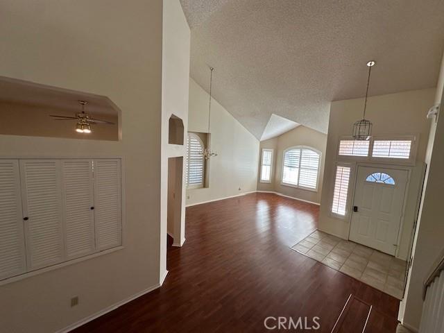 foyer featuring ceiling fan, high vaulted ceiling, hardwood / wood-style floors, and a textured ceiling