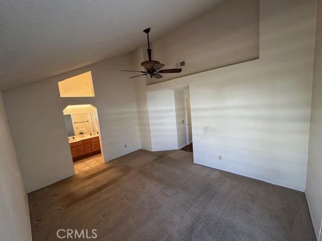 unfurnished bedroom featuring high vaulted ceiling, carpet, connected bathroom, and ceiling fan