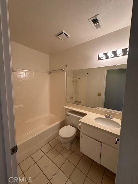 full bathroom featuring tile patterned flooring, vanity, tiled shower / bath combo, and toilet