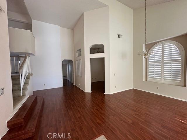 unfurnished living room with a chandelier, a high ceiling, and dark wood-type flooring