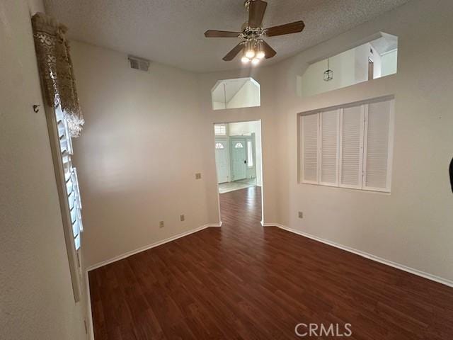 spare room with dark hardwood / wood-style floors, ceiling fan, a towering ceiling, and a textured ceiling