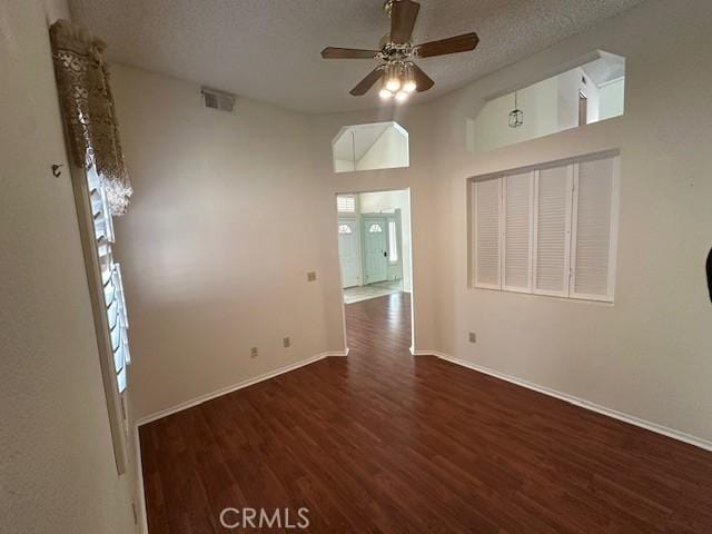 empty room featuring ceiling fan, dark hardwood / wood-style flooring, vaulted ceiling, and a textured ceiling