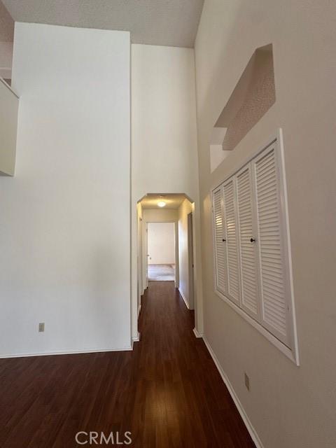 corridor with dark hardwood / wood-style flooring and a towering ceiling