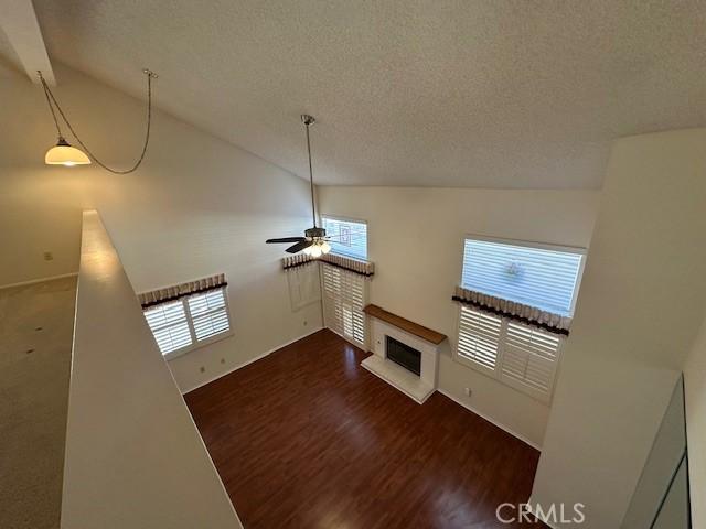 unfurnished living room featuring ceiling fan, high vaulted ceiling, a healthy amount of sunlight, and dark hardwood / wood-style floors