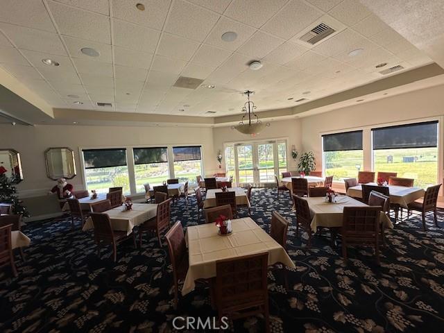 dining space featuring french doors, a raised ceiling, and carpet floors