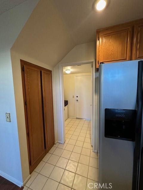 kitchen with lofted ceiling, light tile patterned flooring, and stainless steel refrigerator with ice dispenser