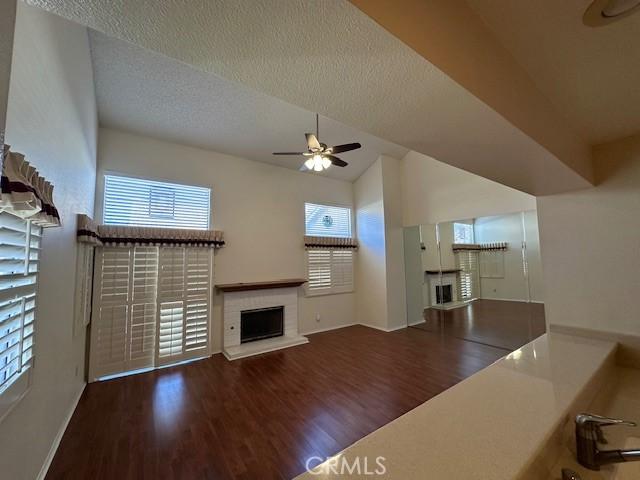 unfurnished living room featuring a textured ceiling, ceiling fan, and dark wood-type flooring