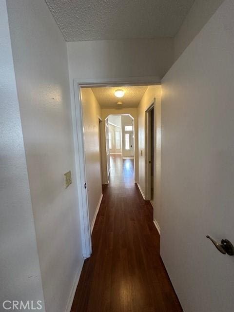 corridor with dark hardwood / wood-style flooring and a textured ceiling