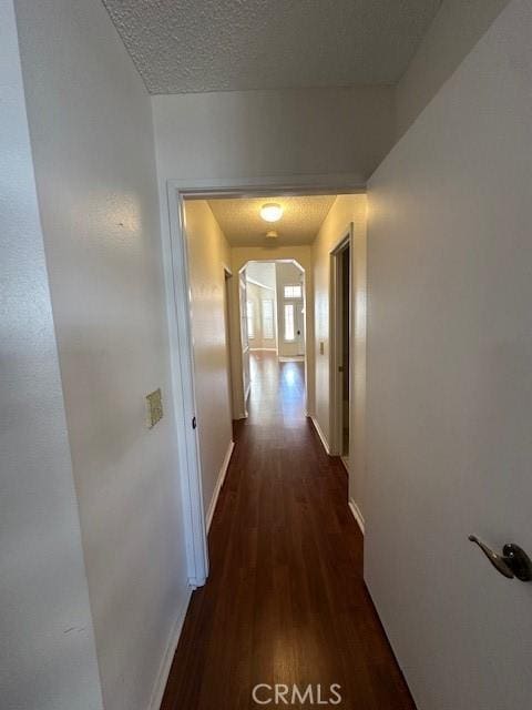 hallway featuring dark hardwood / wood-style flooring and a textured ceiling