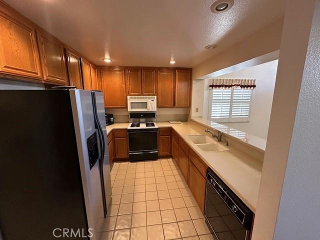 kitchen with light tile patterned flooring, white appliances, and sink