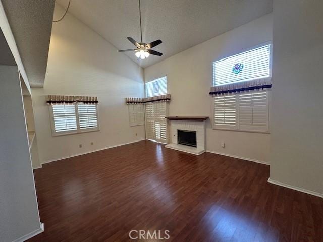 unfurnished living room featuring plenty of natural light, ceiling fan, dark hardwood / wood-style flooring, and high vaulted ceiling