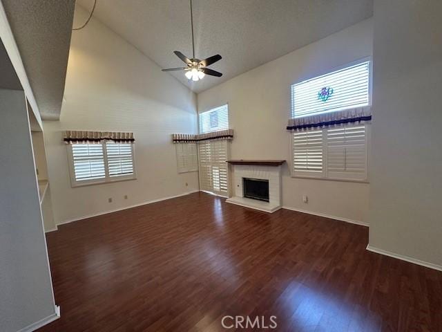 unfurnished living room with dark wood-type flooring, high vaulted ceiling, a brick fireplace, a textured ceiling, and ceiling fan