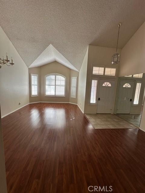 entryway featuring lofted ceiling, a textured ceiling, hardwood / wood-style flooring, and a notable chandelier