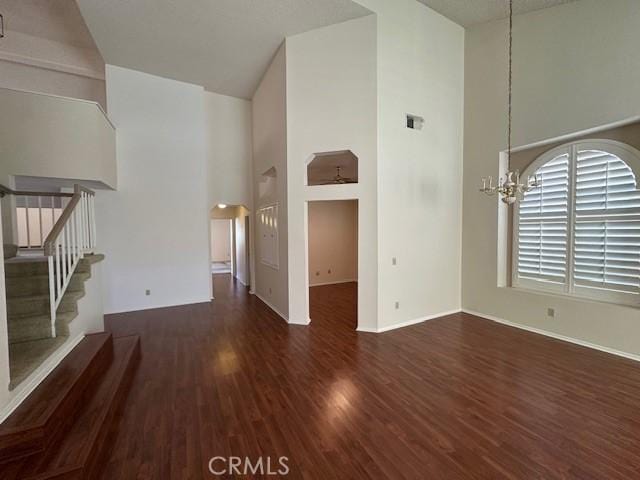 unfurnished living room featuring dark wood-type flooring, a chandelier, and a high ceiling