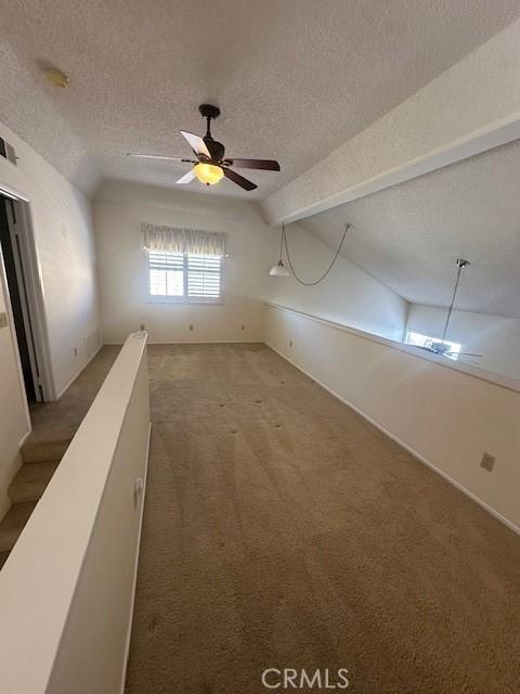 additional living space with vaulted ceiling, ceiling fan, carpet floors, and a textured ceiling