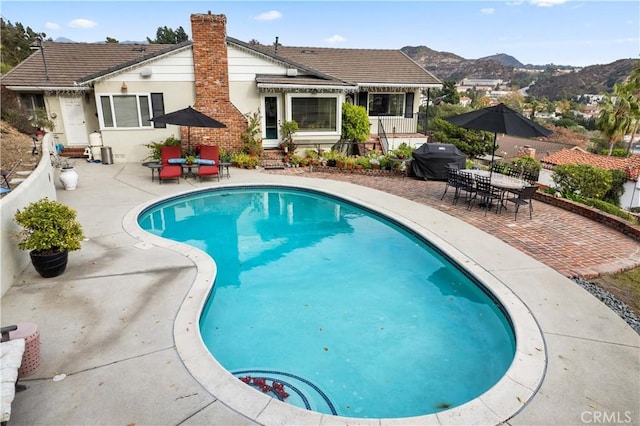 view of pool featuring a mountain view, a patio, and area for grilling