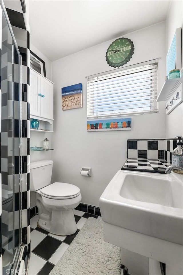 bathroom featuring toilet, a shower, and sink