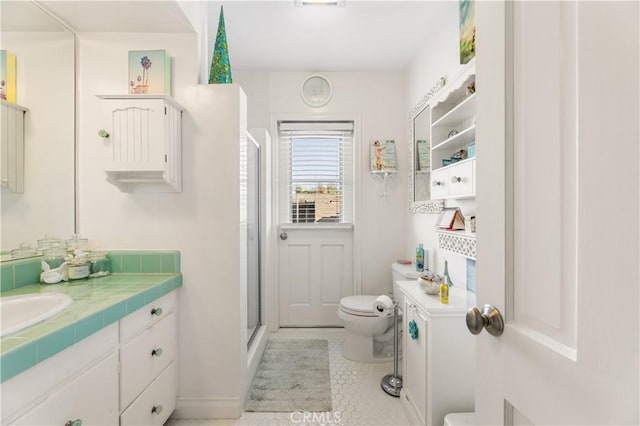 bathroom featuring toilet, vanity, tile patterned floors, and a shower with shower door