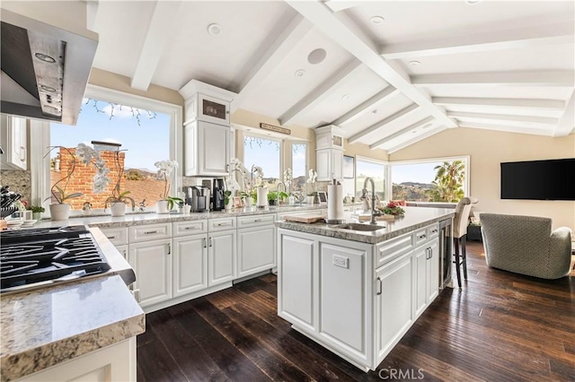 kitchen featuring white cabinetry, sink, lofted ceiling with beams, and a center island