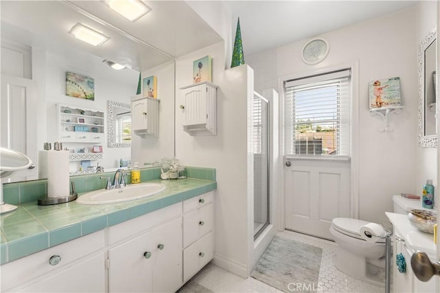 bathroom featuring walk in shower, vanity, tile patterned flooring, and toilet