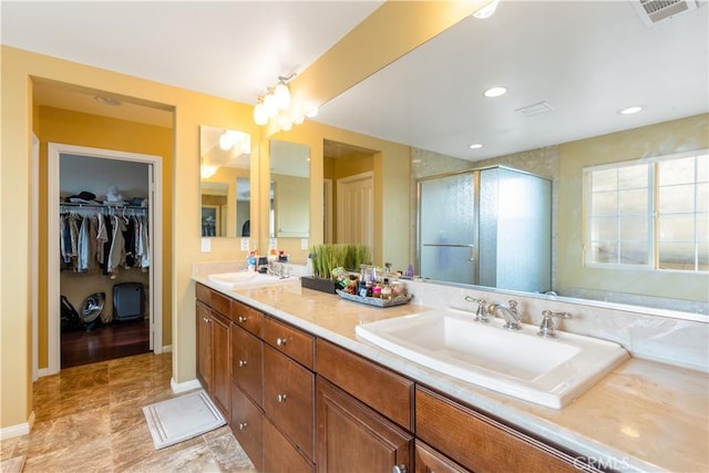 bathroom with double vanity, visible vents, a spacious closet, a sink, and a shower stall