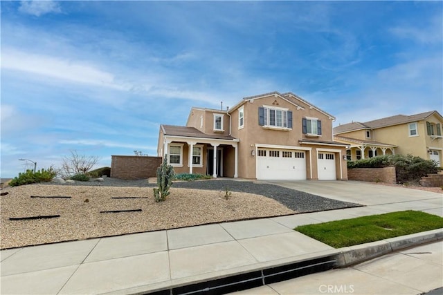 traditional-style home featuring driveway, an attached garage, and stucco siding