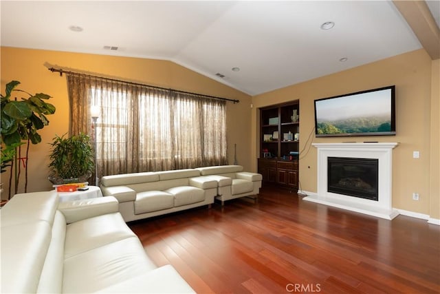 living area with dark wood-style floors, built in features, lofted ceiling, visible vents, and a glass covered fireplace