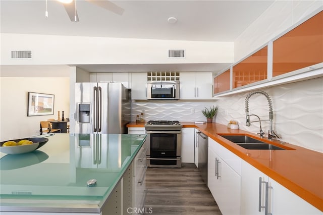 kitchen with backsplash, sink, white cabinetry, dark wood-type flooring, and appliances with stainless steel finishes