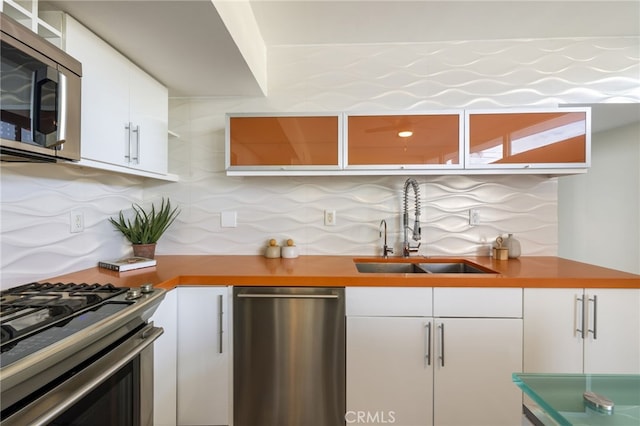 kitchen featuring appliances with stainless steel finishes, white cabinetry, tasteful backsplash, and sink