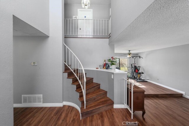 stairs with hardwood / wood-style floors and ceiling fan