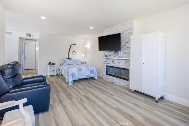 bedroom with a fireplace and light hardwood / wood-style floors