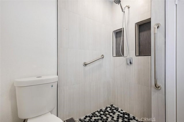 bathroom featuring tiled shower and toilet