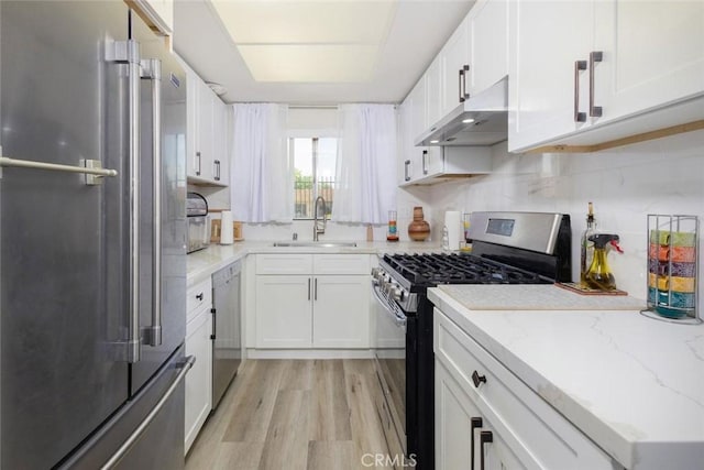 kitchen with stainless steel appliances, white cabinetry, light hardwood / wood-style floors, and exhaust hood