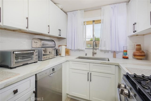 kitchen featuring appliances with stainless steel finishes, light stone counters, white cabinetry, and sink