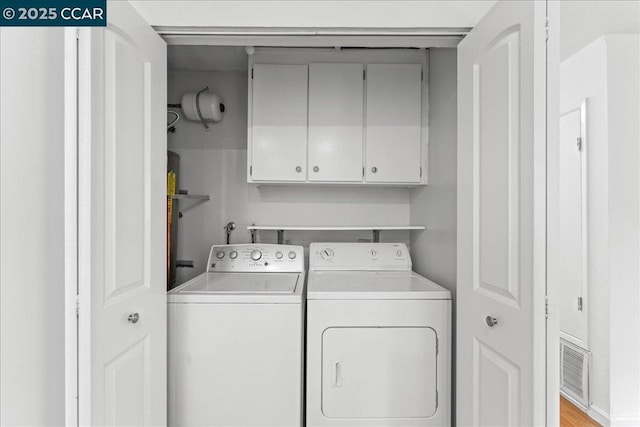 washroom with cabinets and washing machine and clothes dryer