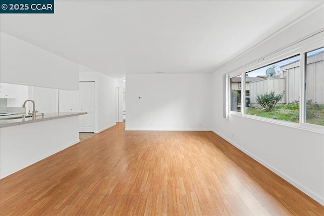 unfurnished living room with sink and light wood-type flooring